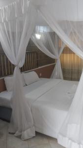 a white bed with white drapes in a bedroom at EQUINE RESORT in Gitura