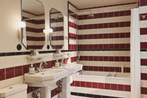 ein Badezimmer mit zwei Waschbecken und einer Badewanne in der Unterkunft Hotel Bella Grande in Kopenhagen