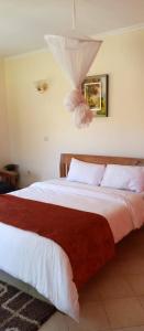 - une chambre dotée d'un grand lit avec des draps blancs et rouges dans l'établissement EQUINE RESORT, à Gitura