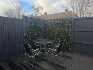 a table and chairs on a deck with a christmas tree at Caroline's One Bedroom House in Northampton in Northampton