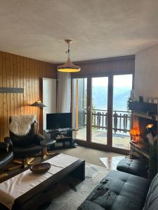 a living room with a couch and a fireplace with a view at Melezes K SKI LIFT & NATURE apartments by Alpvision Résidences in Veysonnaz