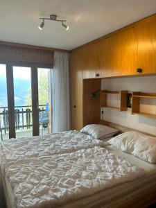 a bedroom with a large bed and a balcony at Melezes K SKI LIFT & NATURE apartments by Alpvision Résidences in Veysonnaz
