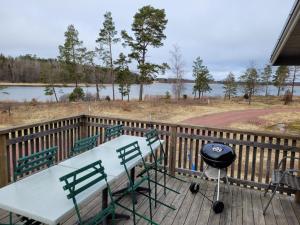 a table and chairs on a deck with a grill at Bastöstugby stuga 16 in Pålsböle
