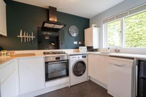 a kitchen with white cabinets and a washer and dryer at Park View- 2 bed apartment close to East Surrey Hospital in Salfords