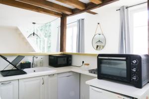 a kitchen with a microwave and a computer on a counter at EXIGEHOME - Beau duplex-15 min Paris/La Défense/Champs Elysées in Suresnes +8 photos