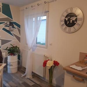 Zimmer mit einer Uhr und einem Fenster mit einer Blumenvase in der Unterkunft au p'tit bonheur in Roye