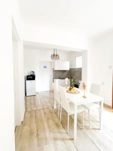 een witte eetkamer met een witte tafel en stoelen bij Rise of Olympus apartmani in Zadar