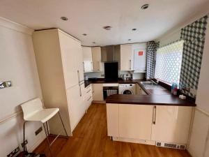 uma cozinha com armários brancos e uma cadeira branca em Bull, 3 bedroom House with Garden and Free Car Park em Stifford