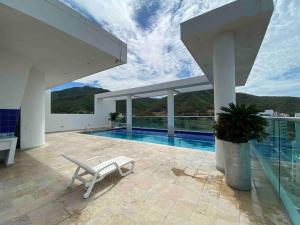a white house with a swimming pool and a chair at Piscina, playa, Relax, Rodadero in Gaira