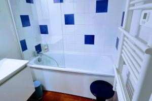 Un baño con bañera blanca y azulejos azules y blancos. en Le MARINE Rez de Jardin direct Plage Parking Privé Climatisé, en Sète