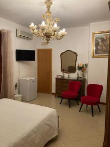 1 dormitorio con 1 cama, 2 sillas rojas y espejo en B&B La Terrazza Dell'Itria en Modica