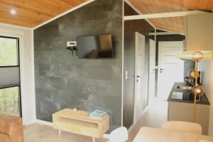 uma sala de estar com uma televisão na parede em Chalet Lodge em Drijber