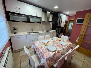 une cuisine avec une table et des chaises et une cuisine avec des placards blancs dans l'établissement Casa Amelia Noia, à Noia