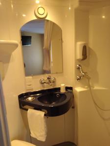uma casa de banho com um lavatório preto e um espelho em Fasthotel Annecy em Seynod