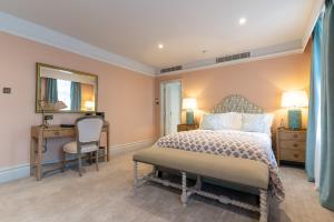 a bedroom with a bed and a desk and a mirror at The Vineyard Hotel in Horsham, Near Gatwick Airport in Horsham