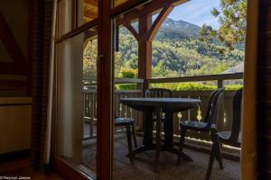 une table et des chaises sur un balcon avec vue dans l'établissement Apparts au Cœur de St-Lary - Piscine Chauffée et Sauna, à Saint-Lary-Soulan