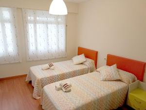 2 Betten in einem Zimmer mit 2 Fenstern in der Unterkunft Sentir Galicia Apartamentos in Redondela