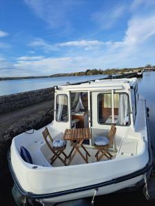 a white boat with two chairs and a table at BATEAU - CANAL DU NIVERNAIS NIEVRE in Bazolles