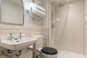 a white bathroom with a toilet and a sink at The Vineyard Hotel in Horsham