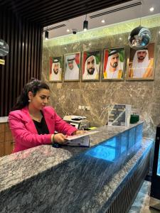 Garden City Hotel Dubai في دبي: امرأة جالسة في مكتب مع الكمبيوتر المحمول