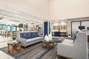 una sala de estar con sofás, sillas y mesas. en Holiday Inn Express & Suites Mobile West I-10, an IHG Hotel, en Tillmans Corner