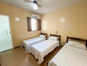 a room with two beds and a window at Elite Palace Hotel in Pará de Minas