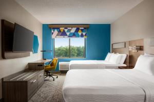ティルマンズ・コーナーにあるHoliday Inn Express & Suites Mobile West I-10, an IHG Hotelのベッド2台、薄型テレビが備わるホテルルームです。
