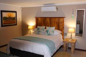 ein Schlafzimmer mit einem großen Bett und zwei Lampen in der Unterkunft The Leopard Tree in Polokwane
