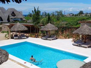 un uomo che nuota in una piscina in un resort di Ocean zuri villa a Watamu Altre 13 foto
