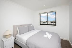 sypialnia z białym łóżkiem z pluszowym misiem w obiekcie Lovely 4 bedrooms house to Ed station w mieście Ingleburn