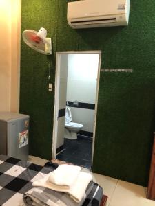 a bathroom with a toilet and a green wall at Hotel thái bảo in Thôn Mỹ Phước