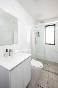 biała łazienka z toaletą i umywalką w obiekcie Lovely 4 bedrooms house to Ed station w mieście Ingleburn