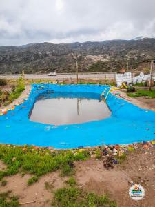 una gran piscina de agua azul en un campo en BusTel Hostel en Bus en Potrerillos