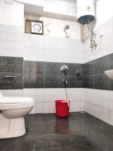 a bathroom with a toilet and a red bucket at Hotel Sonar Tori in Gangtok