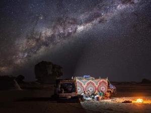 a truck parked in the desert under a starry sky at White Desert Safari in Bawiti