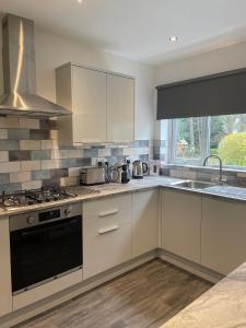 uma cozinha com armários brancos e um forno com placa de fogão em The Eves em Corbridge