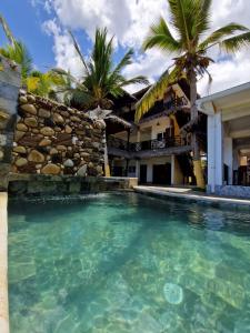 a swimming pool in front of a house with palm trees at Ô Bleu Azur in Antsatrakolo