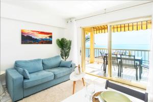 a living room with a blue couch and a balcony at Roquebrune plage - Terrace splendid sea view - BW in Roquebrune-Cap-Martin
