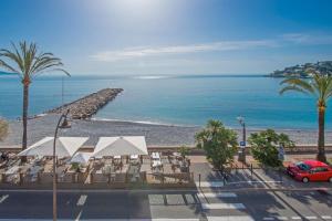 a view of a beach with palm trees and a red car at Roquebrune plage - Terrace splendid sea view - BW in Roquebrune-Cap-Martin