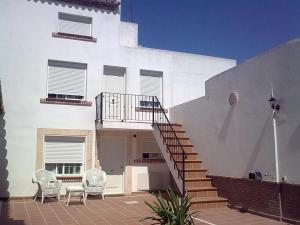 Casa blanca con 2 sillas y escalera en Apartamentos Jerezanos, en Jerez de la Frontera