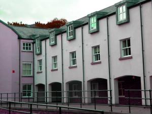 a row of white buildings with green windows at Durham Moonlight Apartment in Durham