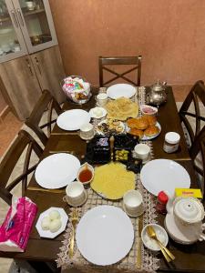 a wooden table with white plates and food on it at Riad malak in Marrakesh