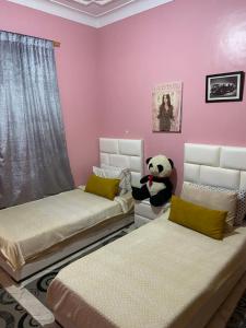 a bedroom with two beds and a stuffed panda bear at Riad malak in Marrakesh