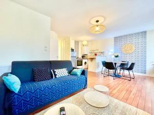 a living room with a blue couch and a kitchen at Brest Centre - Appartements - Le Vauban - Lumineux - Centre Ville - Proche Boutiques et Restaurants in Brest