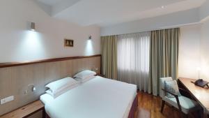 1 dormitorio con 1 cama blanca grande y escritorio en Luxury Skopje Apartments Premium, en Skopje