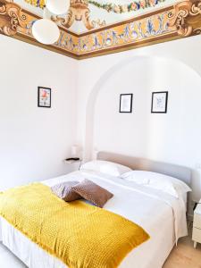 a white bedroom with a yellow blanket on a bed at Intrecci B&B in Terlizzi