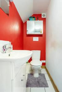 a red bathroom with a toilet and a sink at The Barn @ Box Farm in Middlezoy