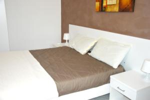 a bedroom with a bed with white pillows at Helios Rooms in Flumini di Quartu