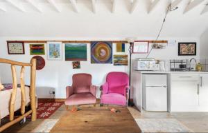 two pink chairs in a room with a kitchen at The Barn @ Box Farm in Middlezoy