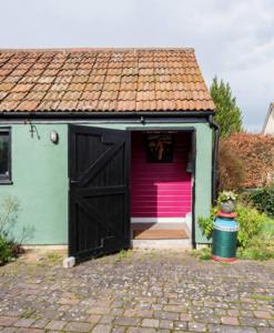 a small house with a pink door and a garage at The Barn @ Box Farm in Middlezoy
